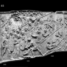Scene 65/LXV: Following flight and refuge by the Dacians into a forest (trees on the far left, cast 160), legionaries construct a fort on hilly ground, a job that requires the excavation of a trench (vallum) in the foreground, at the foot of the walls (Richmond sees the two pairs of excavators in a rivalry with one another; 1935: 22).  One soldier uses a mallet to pound on a vertical support.  A band of auxiliaries approaches from the left. 
From casts 160-163, now in the Museo della Civiltà Romana, Rome. Compare Cichorius Pl. XLVI, scene 65 and Coarelli Pls. 69-70.  RBU2011.7148-composite.